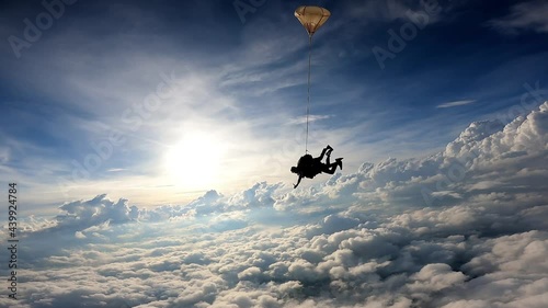 Tandem skydiving in a dramatic sky. The sun illuminates the clouds at the end of the day. Slow motion movie.
