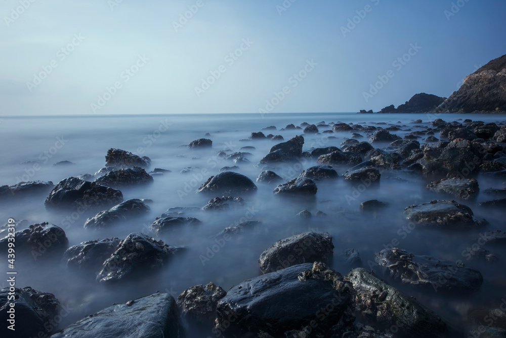 Beach with lots of rocks and water waves with Slow shutterspeed. Smooth effect on water, long exposure photography on a Costal Area..