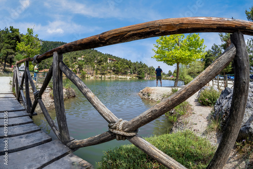 Beletsi Lake in Athens - Greece. Panoramic view to Beletsi Lake while standing on the wooden bridge of the lake and looking through the wooden railings. Man is standing under a tree admiring the view