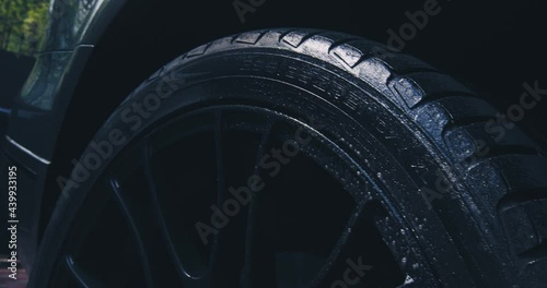 Close up of washing wheel tyre with spraying soapy water in car wash. Exterior car detailing concept