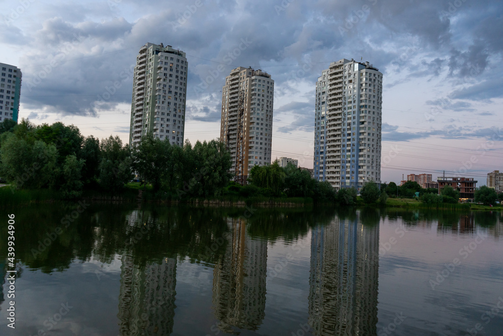 Three tall houses by the lake. Residential complex near the lake. Reflection.