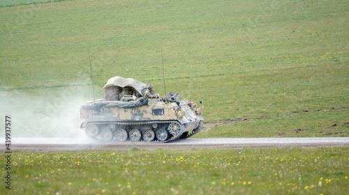 british army FV432 Bulldog fighting vehicle hurtling along a stone track, fully loaded with troop bergens under a camouflage tarpaulin cover  photo