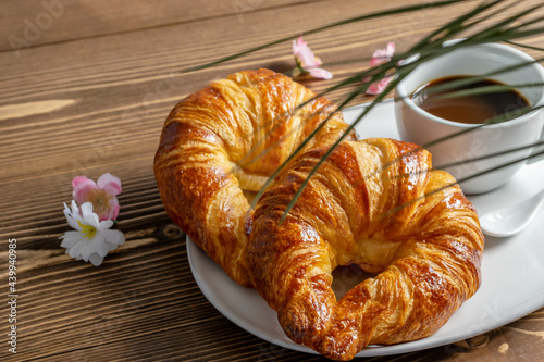 Croissants and a cup of coffee on the wooden background. Breakfast with fresh tasty croissants and coffee. Closeup picture, top view.