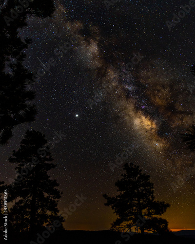 Via lactea en las montañas de Arizona abajo de las estrellas con arboles de pinos con vista de estrella fugaz y Júpiter durante atardecer