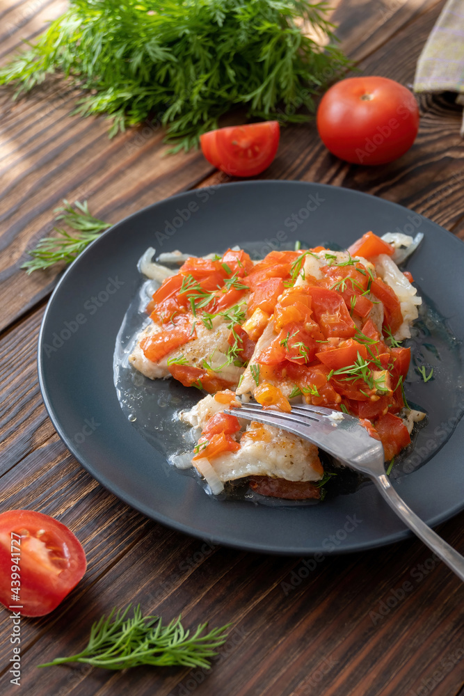 Fish with tomatoes and dill on the flat dish on wooden table. Flounder fillet and vegetable garnish for healthy home lunch. Fish with tomatoes and dill on the flat dish on wooden table. Flounder fillet and vegetable garnish for healthy home lunch.