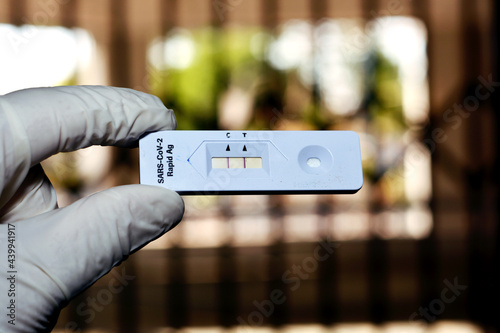 A medical personnel shows a positive result of SARS-COV-2 Rapid Ag test, positive Covid-19 corona virus test on a blurred background, novel pandemic coronavirus 2019 found in Wuhan, China photo