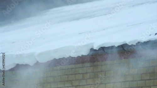 Snow blowing of an apartment roof during a blizzard