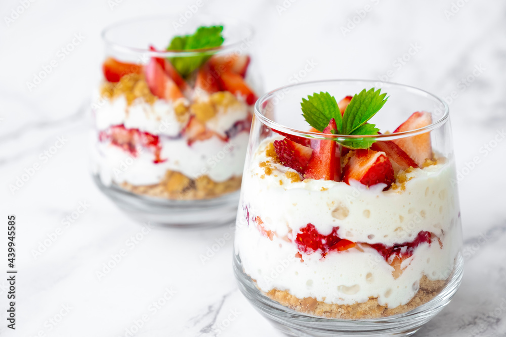 Strawberry dessert with cream cheese or yogurt, granola and fresh strawberry in glass on marble background. Recipe of simple healthy homemade organic dessert, cheesecake, mousse or berry trifle. Strawberry dessert with cream cheese or yogurt, granola and fresh strawberry in glass on marble background. Recipe of simple healthy homemade organic dessert, cheesecake, mousse or berry trifle.