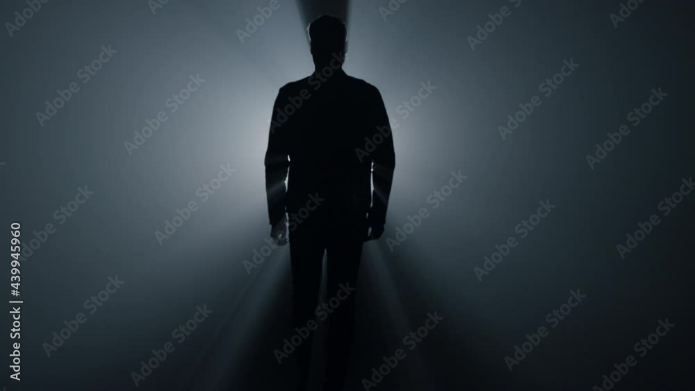 Silhouette man walking in darkness. Male person going straight on in dark.
