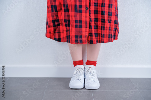 Women's feet in white sneakers on a white background