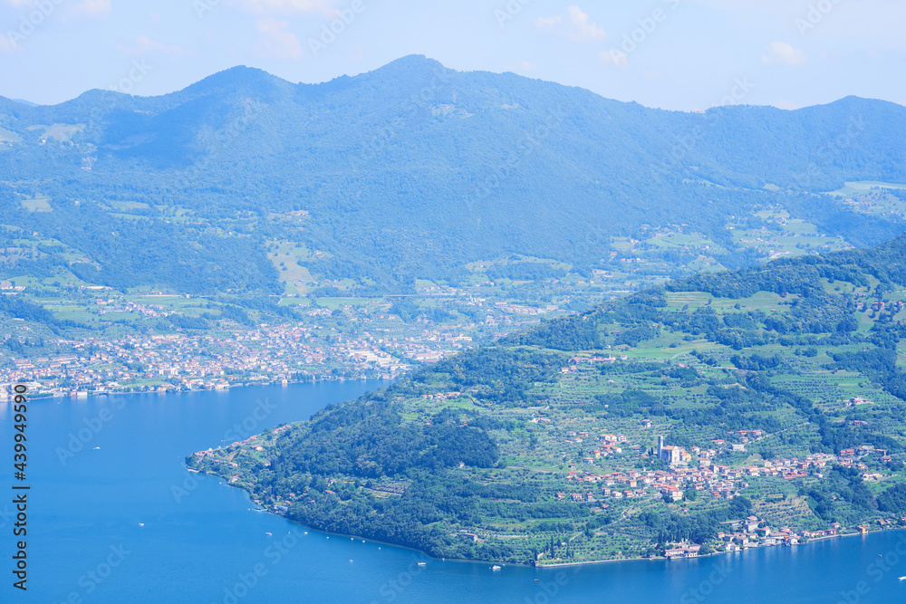 Aerial view of lake Iseo, forested mountains, various villages scattered along the mountain slopes and along the coast. Iseo lake in Brescia province, Lombardy, Italy. Picturesque summer landscape.
