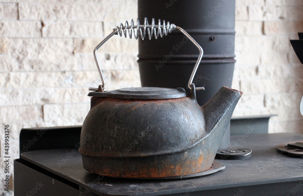 Old black iron kettle on a woodstove Old black iron kettle on a woodstove