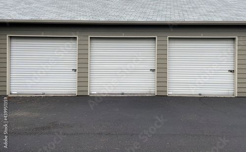 White garage doors with numbers on buildings with tan siding