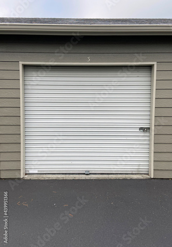 White garage doors with numbers on buildings with tan siding