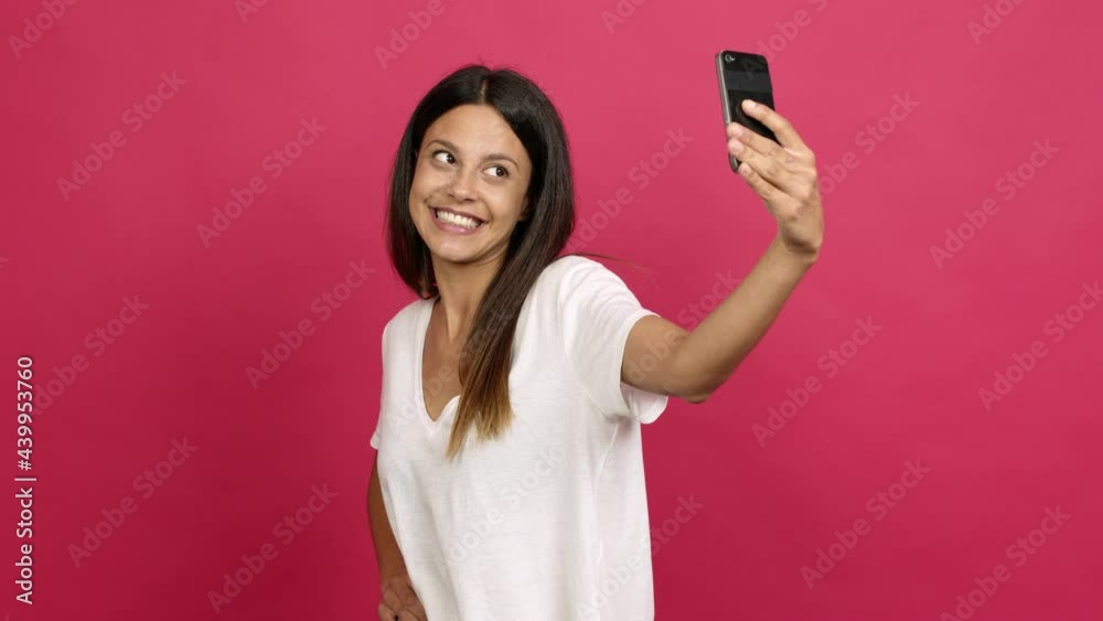 Young woman using mobile phone and doing a selfie over isolated background Young woman using mobile phone and doing a selfie over isolated background