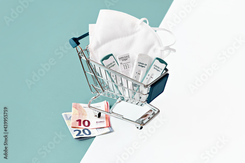 Cost of shnelltest, rapid corona test in German language. Shopping cart with covid 19 antigen tests and money. Mismanagement, embezzlement in rapid COVID testing centers, wasting taxpayers' money.