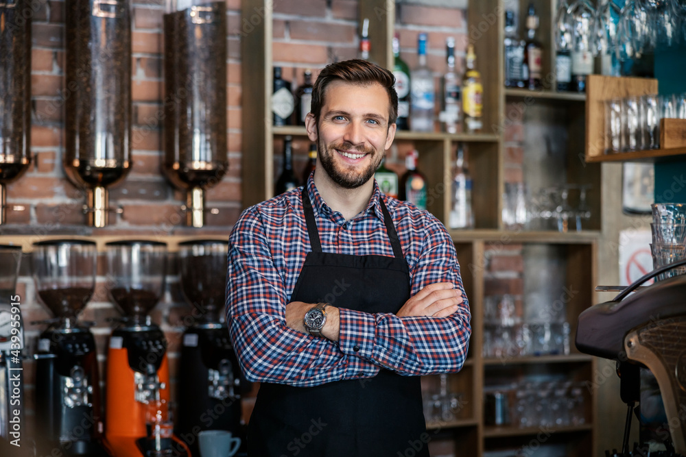 Waiter at the restaurant. The handsome server wears a plaid t shirt and