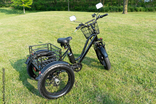 Electric trike or bicycle in the park in sunny summer day. Unfiltered, with natural lighting. E motor and power battery of the three wheel bike. Ecology and green energy concept. Ev – electric vehicle photo