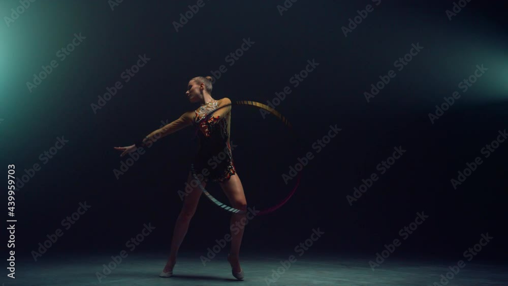 Flexible gymnast spinning hula hoop. Young woman practicing rhythmic gymnastics Flexible gymnast spinning hula hoop. Young woman practicing rhythmic gymnastics