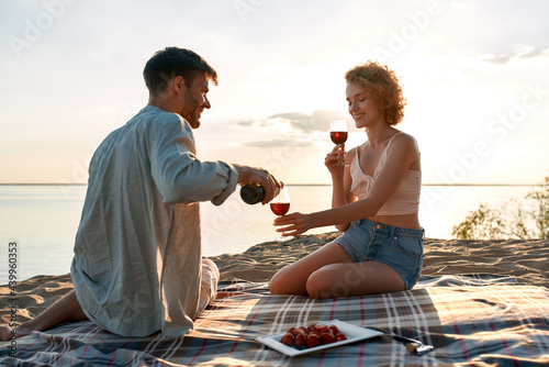 Attractive young caucasian couple filling glasses with wine