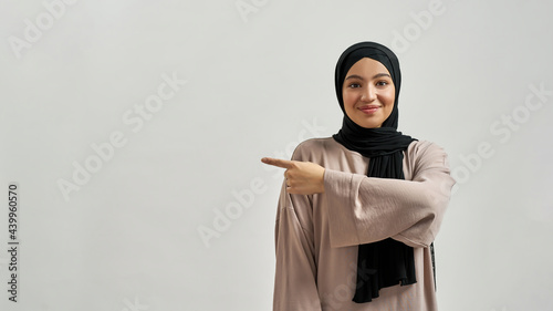Stampa su tela Happy young arabian woman in hijab pointing to side