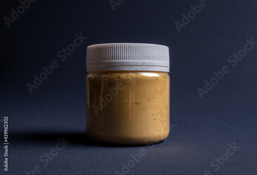 A pot containing resin of a yellow glitter color on a dark black background. Used for various purposes in industry and at home in the adaptation of furniture and objects for interior decoration.