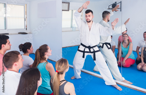Experienced trainer karate to pupils of different age in the room