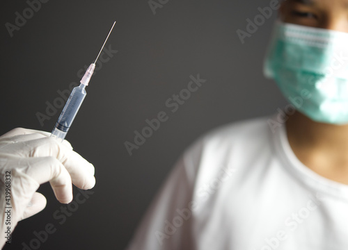 Vaccine concept.Close up hand holding syringe make injection to patient in medical mask.