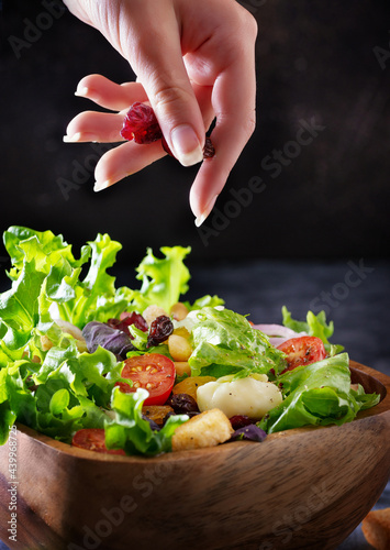 the person holding berries and put them in  a salad