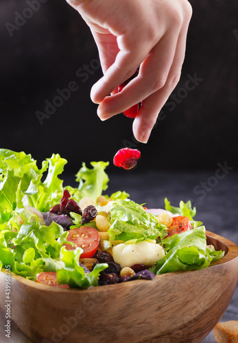 hand holds pepper shaker and sprinkles salad