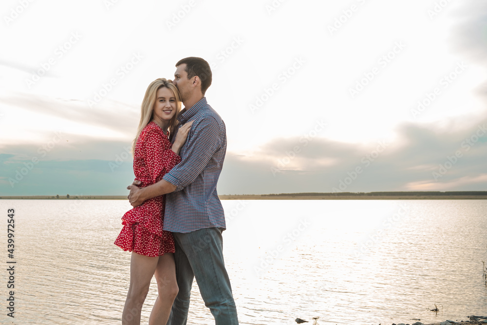 a young couple embraces against the backdrop of a beautiful sunset a young couple embraces against the backdrop of a beautiful sunset