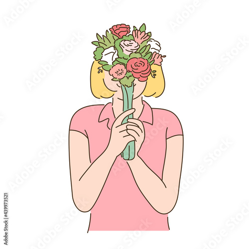 A woman is holding a flower in her hand and covering her face.