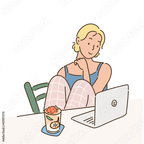 A girl is sitting comfortably at home and looking at a laptop.