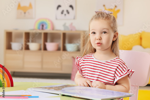 Little girl reading book in room