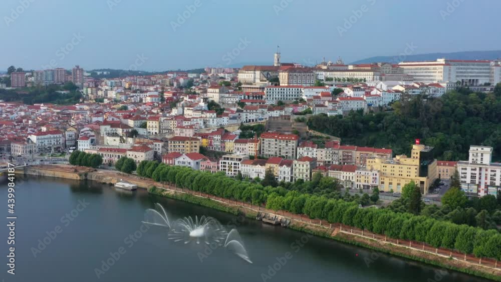 Aerial track shot showing beautiful cityscape of Coimbra located on hill and Rio Mondego River in Portugal Aerial track shot showing beautiful cityscape of Coimbra located on hill and Rio Mondego River in Portugal
