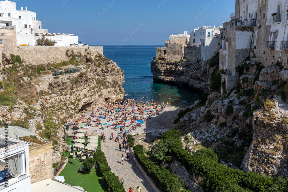  People relax and swimming on lovely beach Lama Monachile in Polignano a Mare, Adriatic Sea, Apulia, Bari province, Italy,