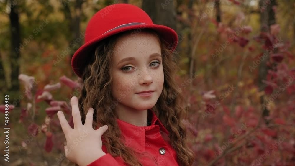 Portrait of a red-haired girl with freckles in a red coat and hat in the autumn Portrait of a red-haired girl with freckles in a red coat and hat in the autumn
