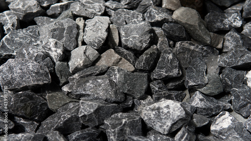 Closeup Pile of Crushed grey stone charcoal color or road metal texture background with natural sunlight © 9gifts