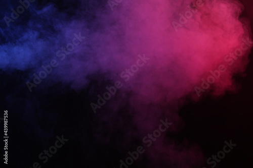 Artificial magic smoke in red-blue light on black background