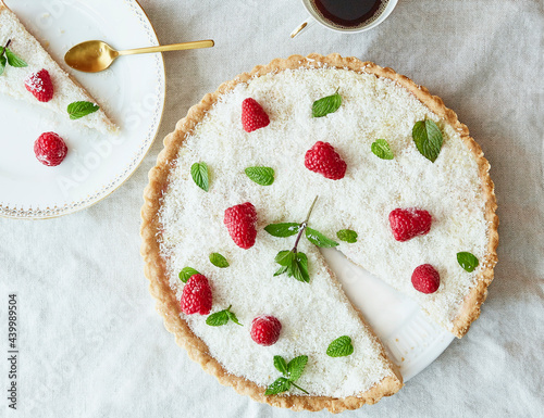Cake with coconut sprinkles, raspberries and mint leaves