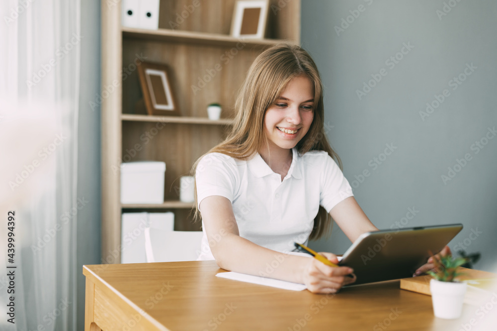 The girl studies at home with a digital tablet and does homework at school. Distance learning online education The girl studies at home with a digital tablet and does homework at school. Distance learning online education