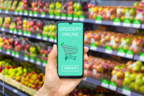 Online grocery delivery app in a mobile phone. Food market service in smartphone with shopping cart. Grocery delivery background concept. Empty blank screen 