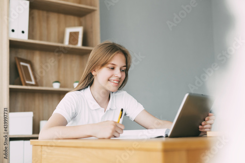 The girl studies at home with a digital tablet and does homework at school. Distance learning online education