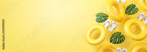 Summer Banner Yellow Background. Flip Flops, Leaf and Inflatable Swimming Ring Copy Space 3D Rendering