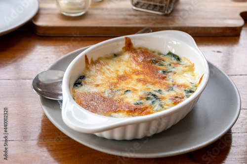 Baked spinach with cheese in a white bowl on the dining table