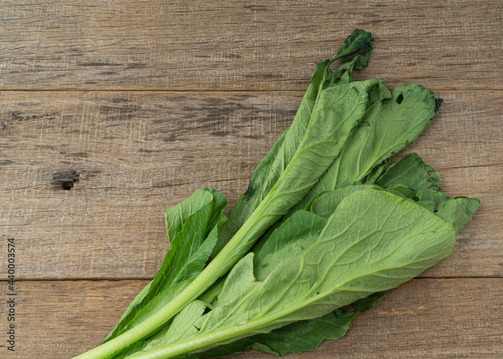Withered mustard green on shabby wooden board. Withered mustard green on shabby wooden board.