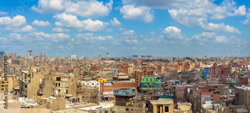 Panorama of shabby buildings with satellite dishes on rooftops against blue cloudy sky in ancient city of Cairo, Egypt