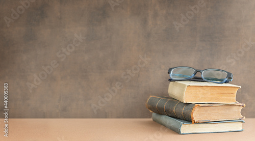 Back to school and education concept. Stack of books and glasses on the top near the blackboard and place for text.