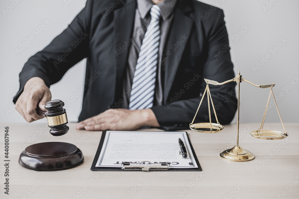 A lawyer or legal advisor holding a small hammer for a judge's table in court is about to pound on the podium to deliver a fair and legal verdict. The concept of correct and fair litigation. A lawyer or legal advisor holding a small hammer for a judge's table in court is about to pound on the podium to deliver a fair and legal verdict. The concept of correct and fair litigation.