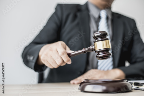 A lawyer or legal advisor holding a small hammer for a judge's table in court is about to pound on the podium to deliver a fair and legal verdict. The concept of correct and fair litigation.